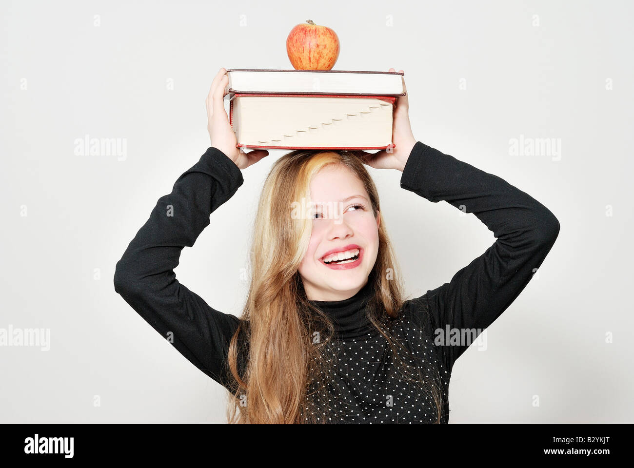 Das Schulmädchen mit Büchern und einen Apfel auf dem Kopf Stockfoto