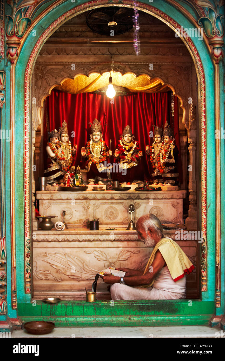 Das Profil von einem Hindu Mann sitzt vor seiner leuchtend roten Altar. Stockfoto