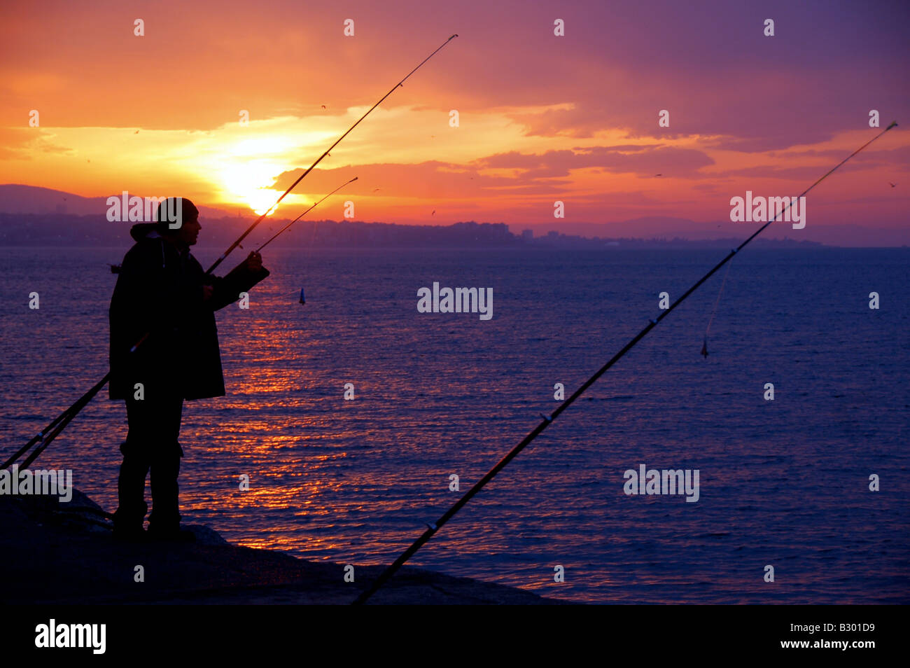 Ein einsamer Fischer wartet auf seinen Fang vor dem Hintergrund der einen wunderschönen Sonnenaufgang auf einer frühen Wintermorgens in Istanbul, Türkei. Stockfoto