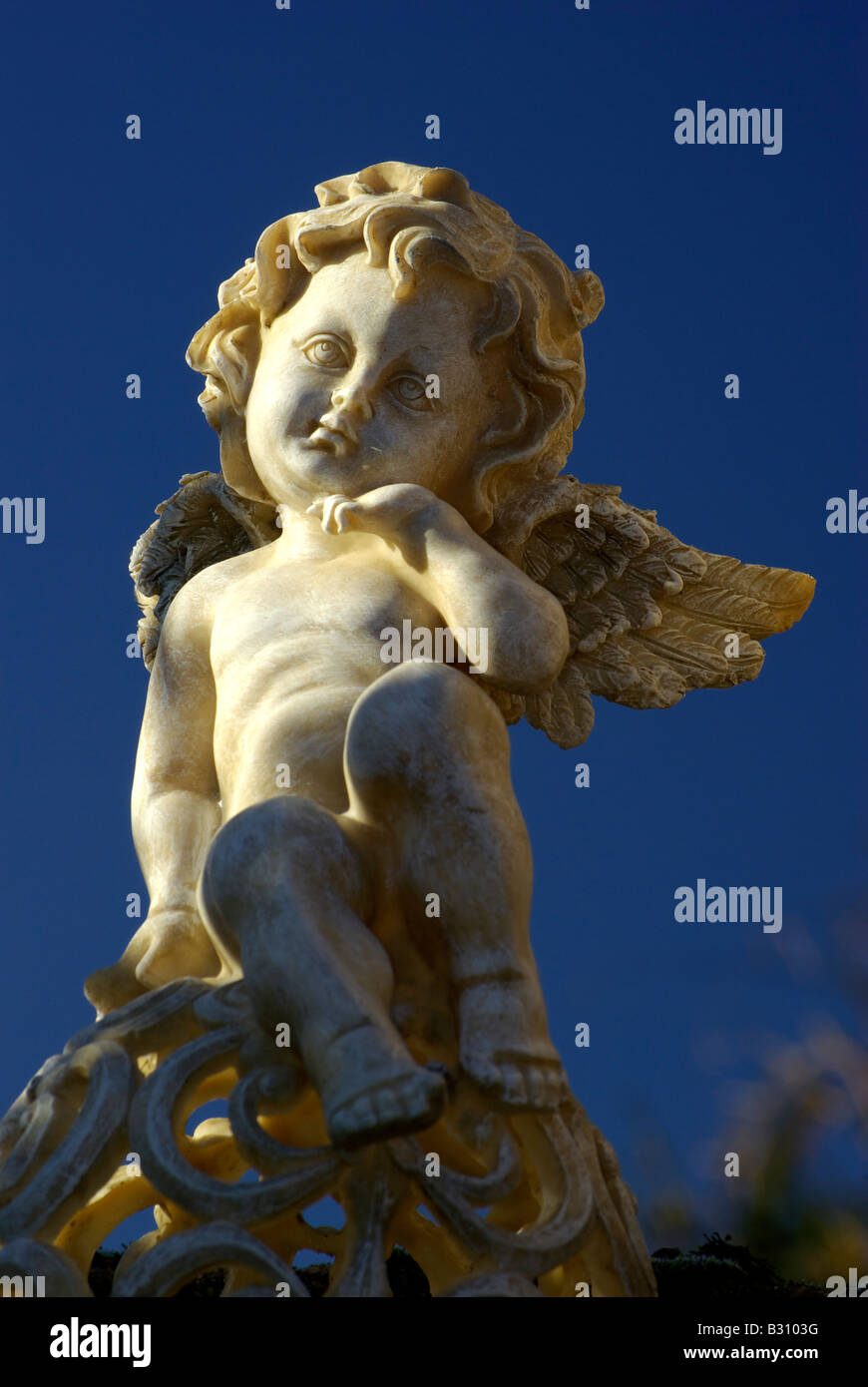 Skulptur von einem unschuldigen Baby Engel Putte auf einem Grab vor blauem Himmel Stockfoto