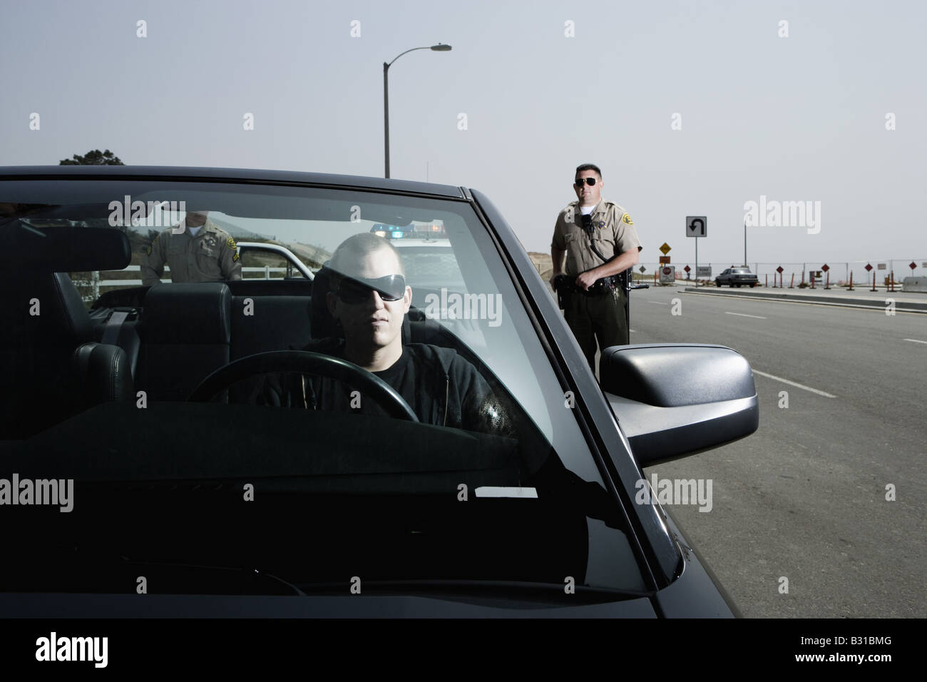 Zwei Polizisten nähert sich Mann in schwarzer Mustang Stockfoto