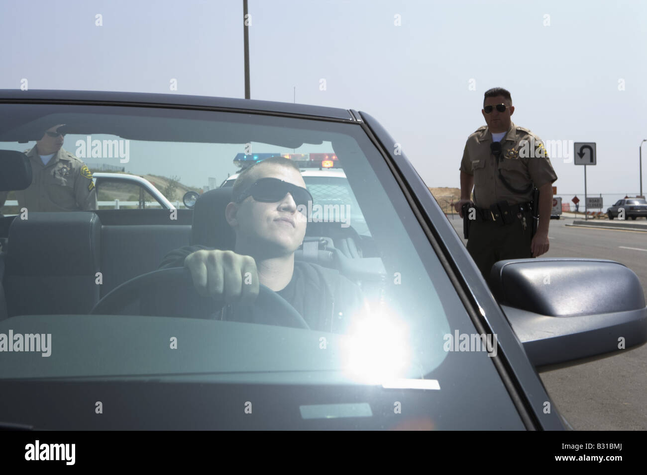 Zwei Polizisten nähert sich Mann in schwarzer Mustang Stockfoto
