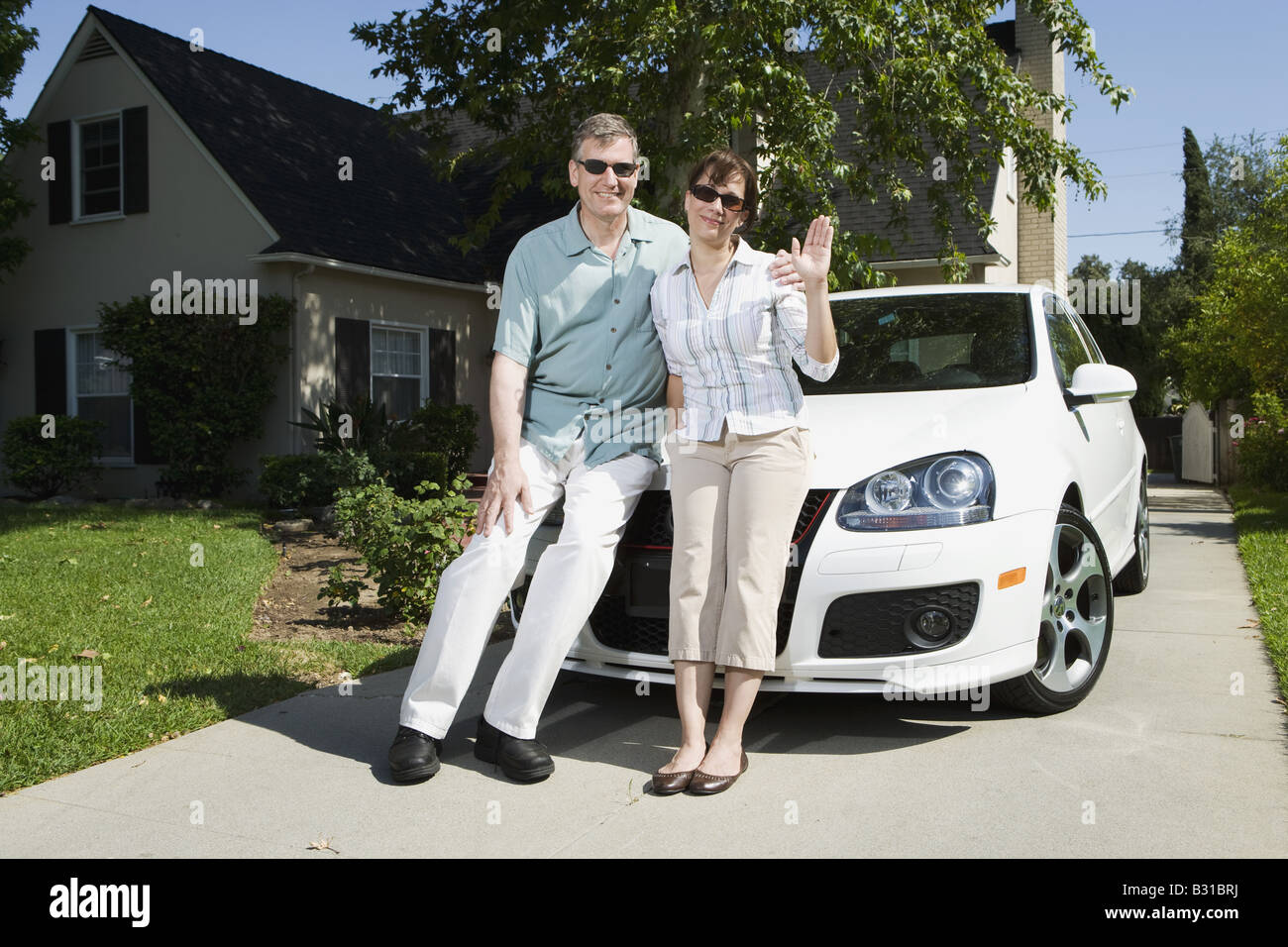 Eltern mit dem weißen VW GTI Auto über Auffahrt Stockfoto