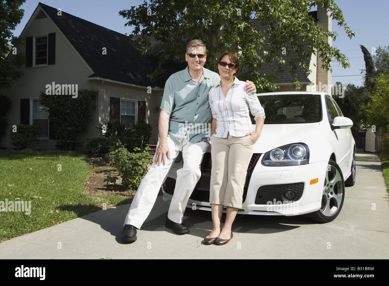 Eltern mit dem weißen VW GTI Auto über Auffahrt Stockfoto