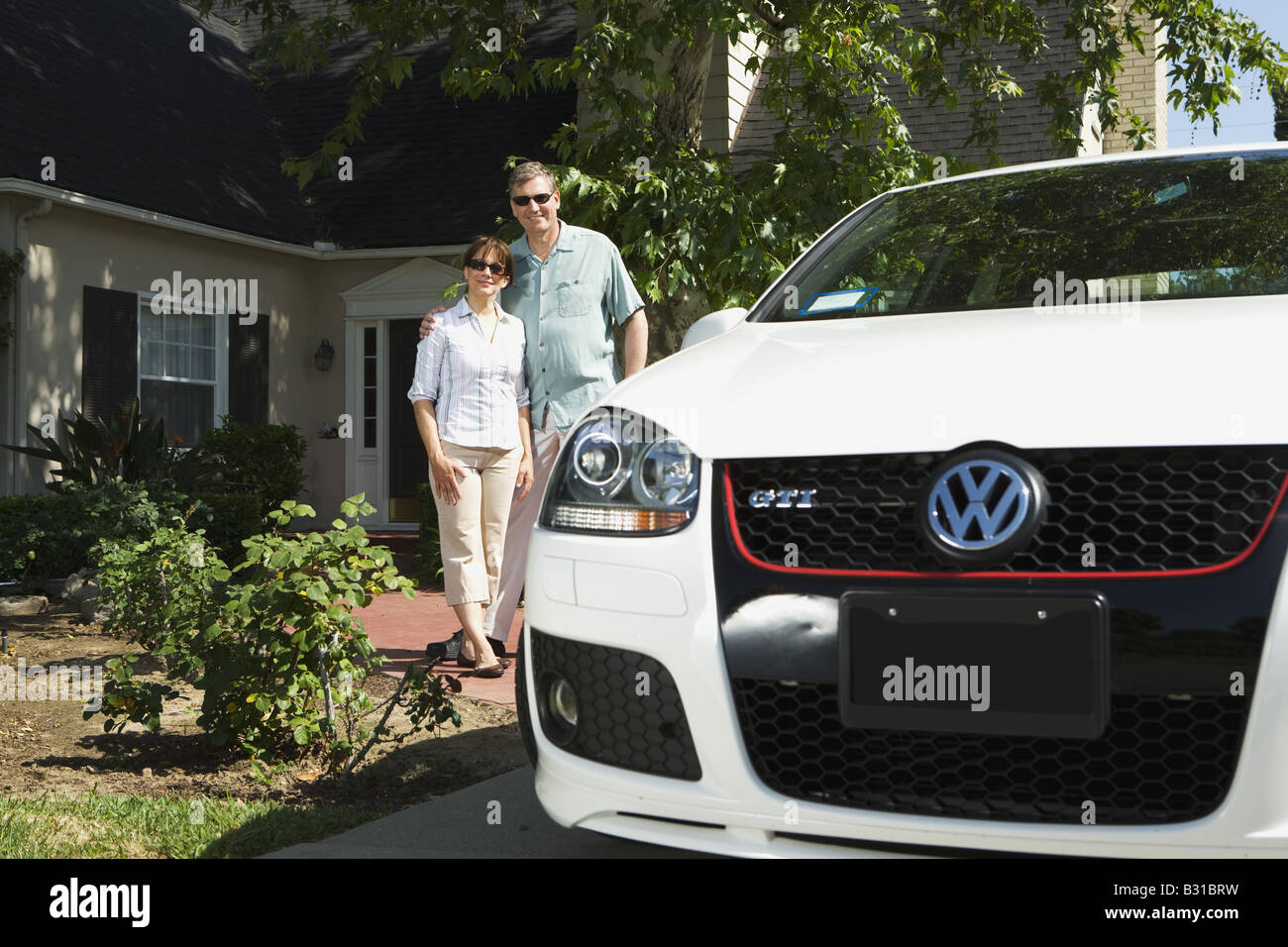 Eltern, die auf weißen VW GTI Auto auf Auffahrt Stockfoto