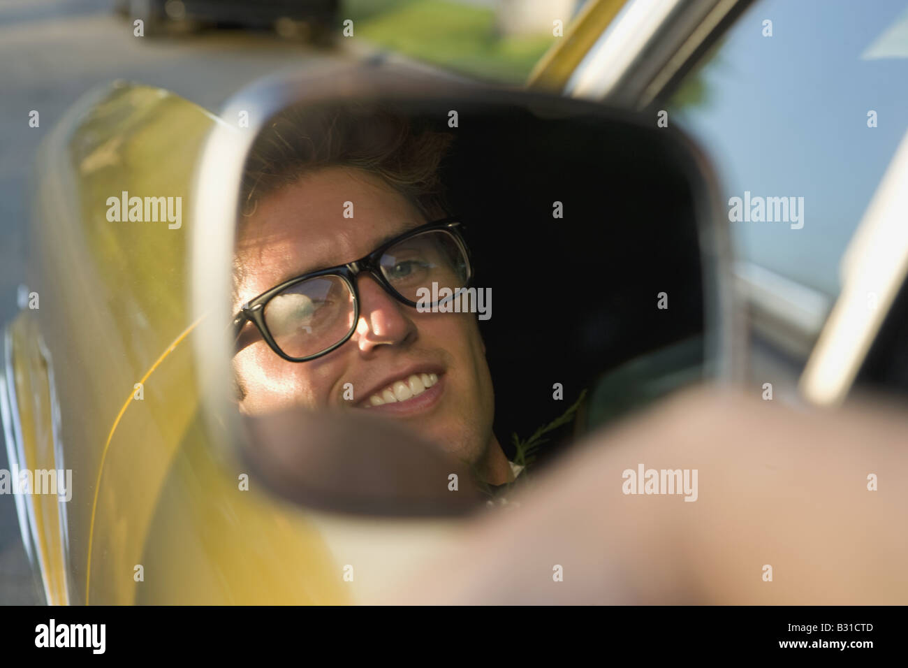 Junger Mann lächelnd in den Spiegel der hinteren Ansicht Stockfoto