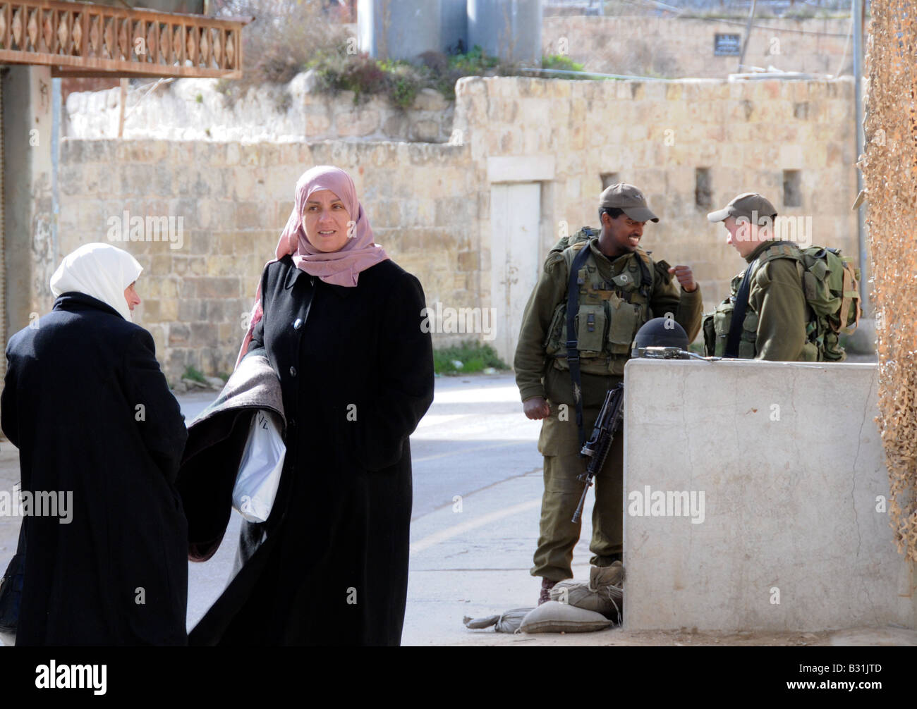Zwei arabische Frauen nähern sich einem kleinen Checkpoint von zwei israelischen Soldaten-ein russischer Immigrant und eine äthiopische Einwanderer. Stockfoto