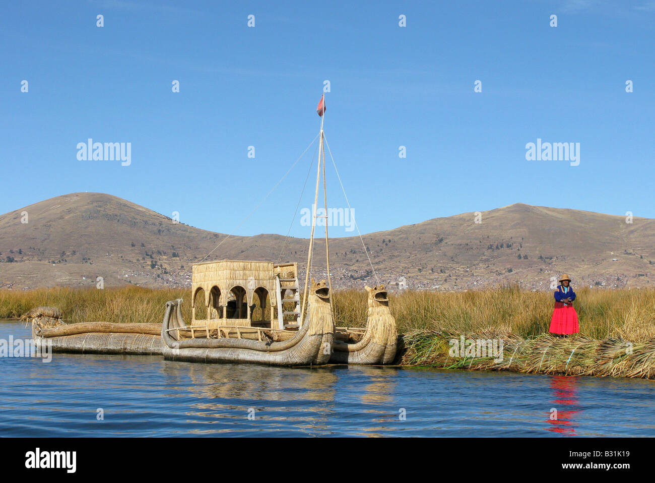 Uros Frauen in der Nähe von einem Reed-Boot auf selbst altmodische schwimmenden Schilfinseln im Titicacasee, Peru Stockfoto