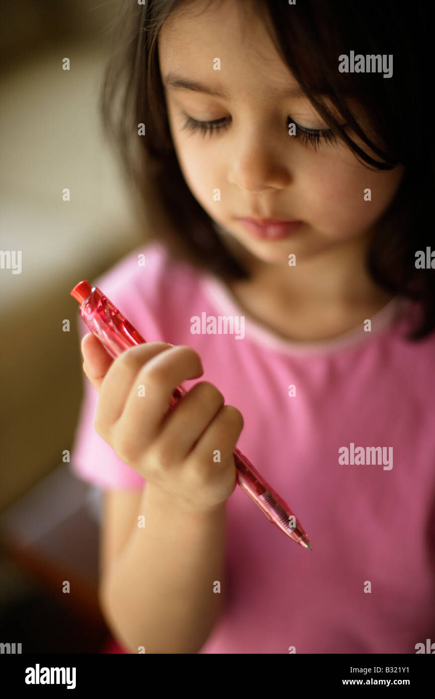 In Anbetracht einer Kugelschreiber Stift fünf Jahre altes Mädchen schaut einen roten Stift Stockfoto