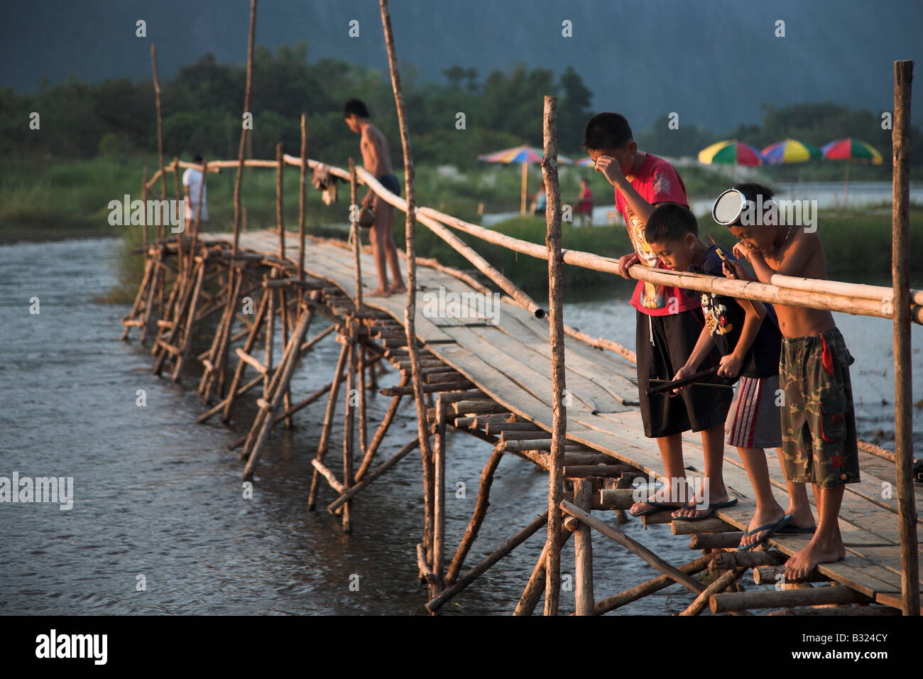 Kinder auf der Holzbrücke über den Nam Song River in Vang Vieng, Zentral-Laos. Stockfoto