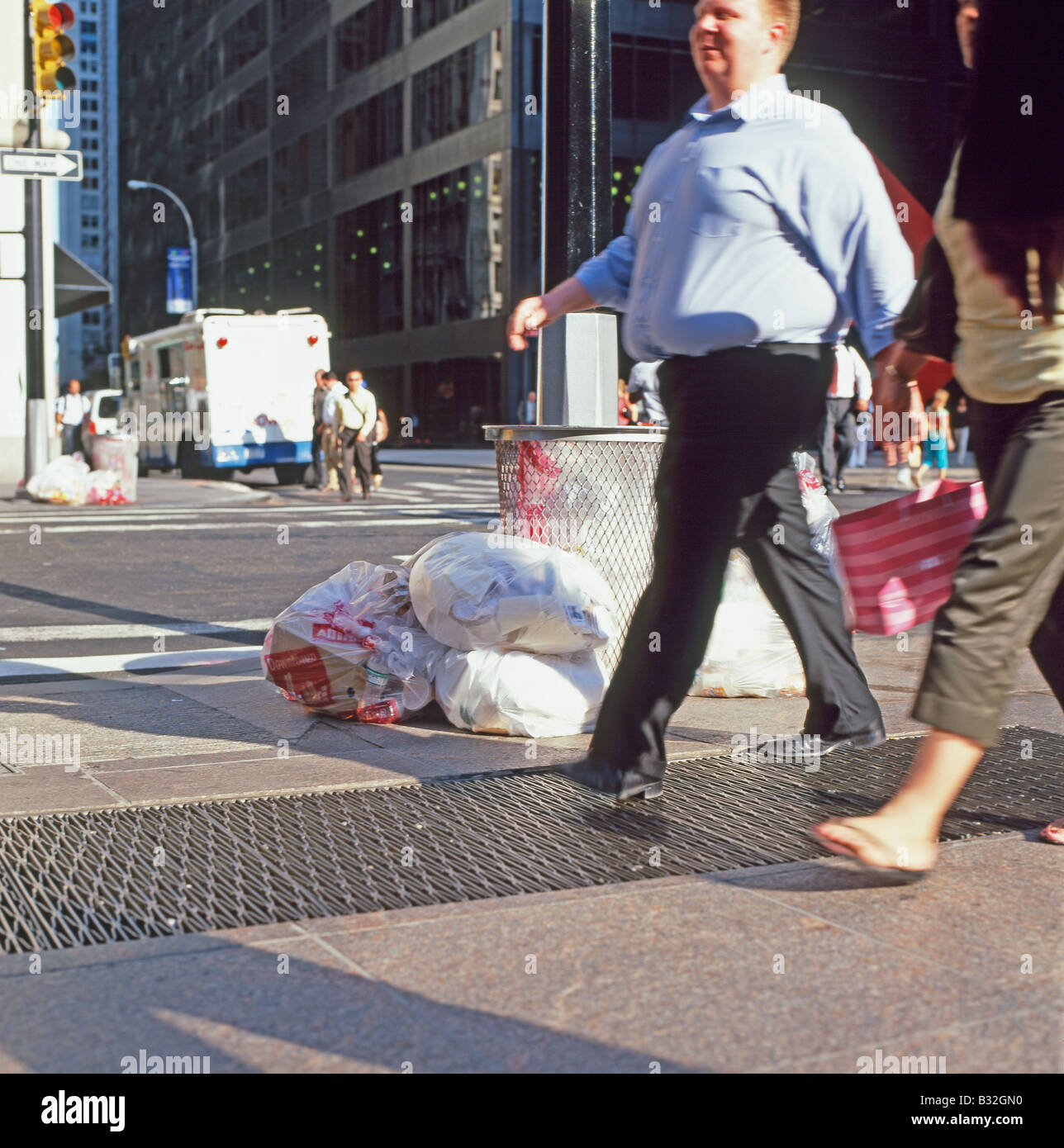 Fußgänger zu Fuß auf dem Gehweg vorbei nicht abgeholte Müllsäcke an einer Straßenecke in New York CIty, USA KATHY DEWITT Stockfoto