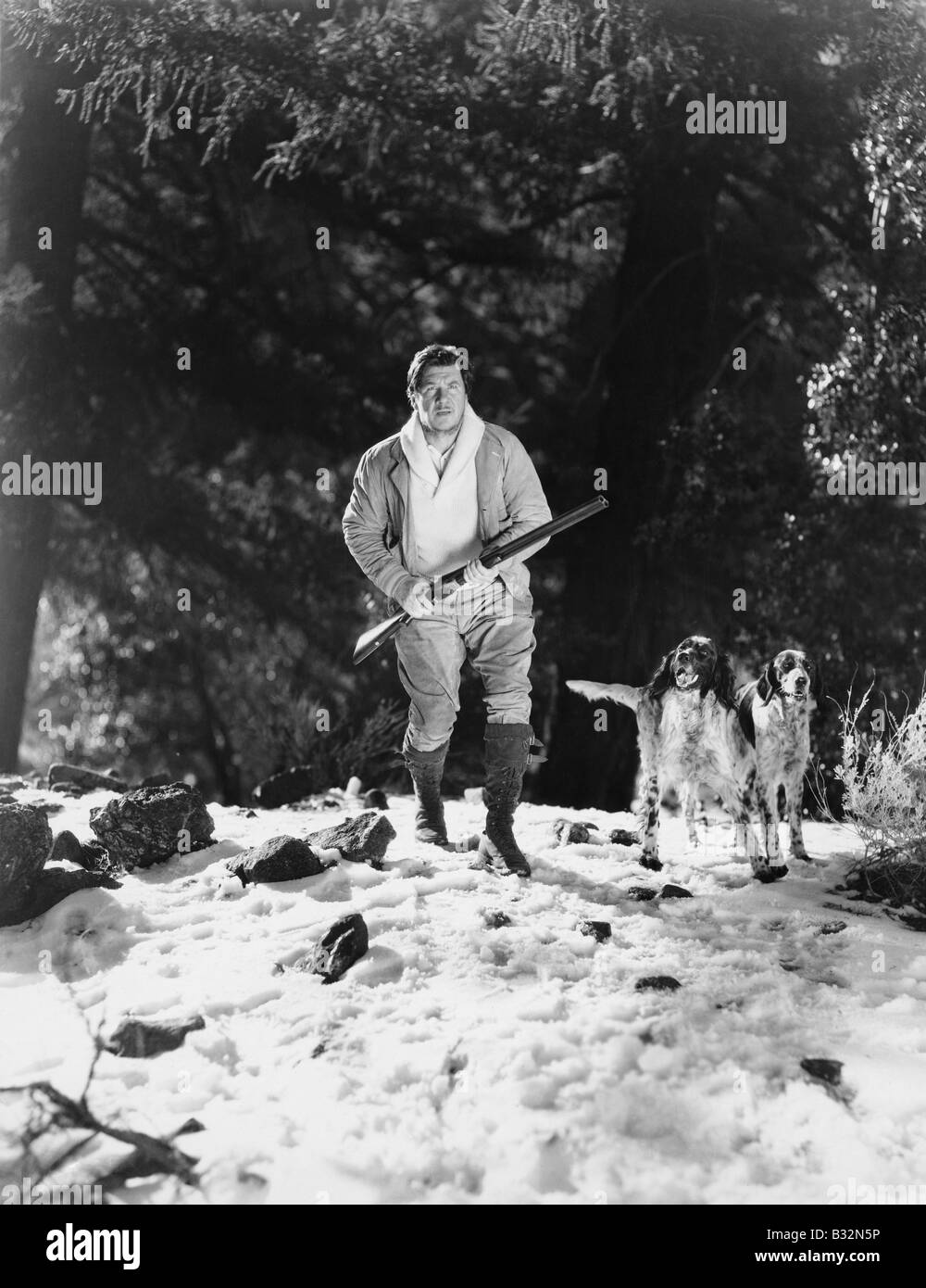 Mann in verschneiten Wäldern mit Hunden jagen Stockfoto