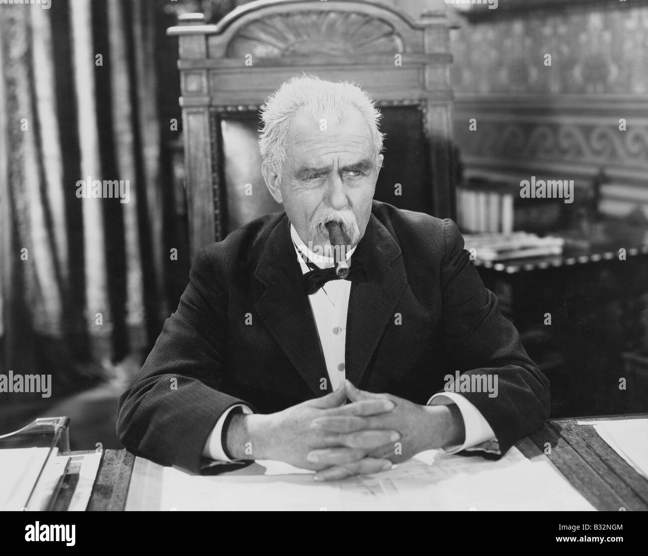 Geschäftsmann rauchende Zigarre am Schreibtisch Stockfoto