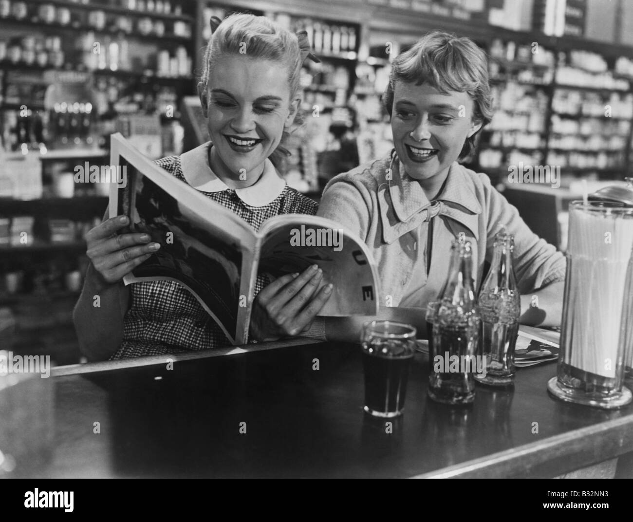 Freundinnen betrachten Magazine bei Soda fountain Stockfoto