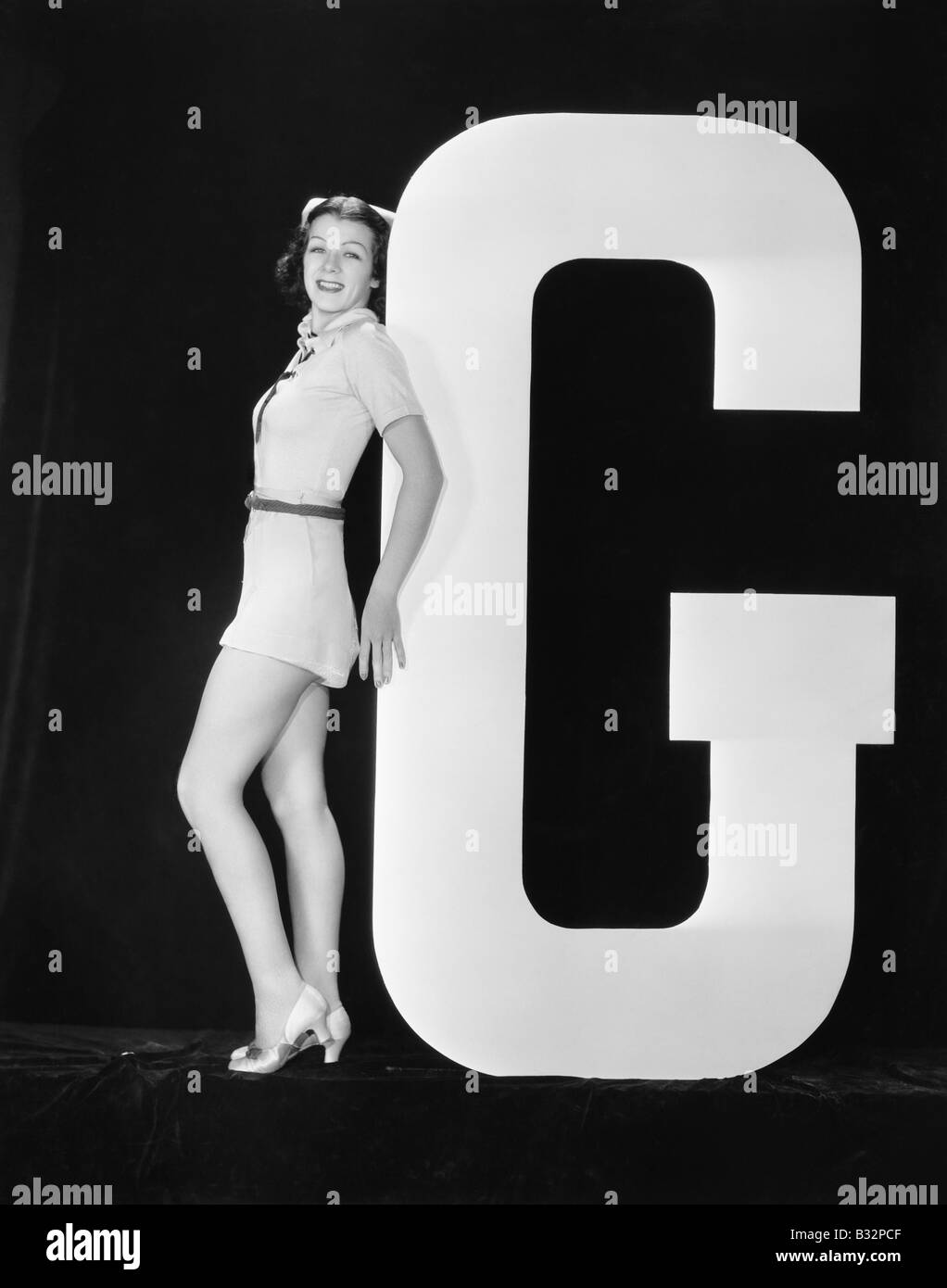 Frau posiert mit riesigen Buchstaben G Stockfoto