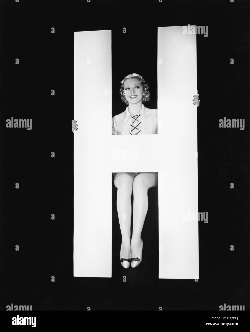 Frau posiert mit riesigen Buchstaben H Stockfoto
