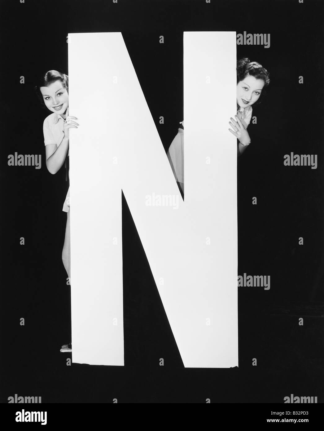 Zwei Frauen, versteckt hinter riesigen Buchstaben N Stockfoto