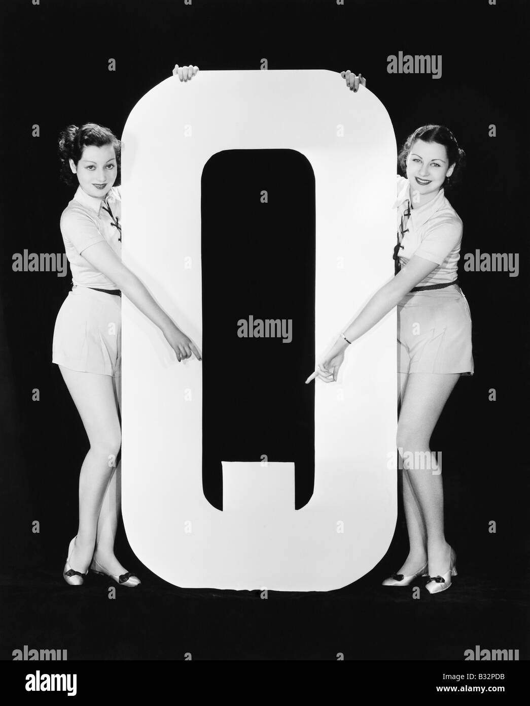 Zwei Frauen zeigen riesige Buchstabe Q Stockfoto