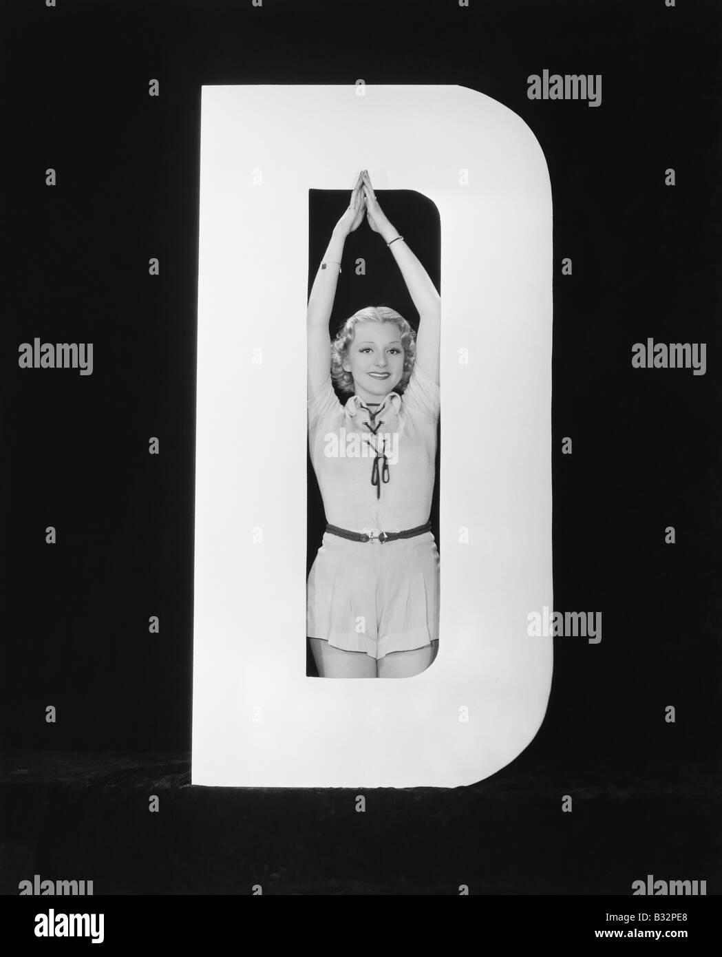 Frau posiert in der Mitte des Buchstaben D Stockfoto
