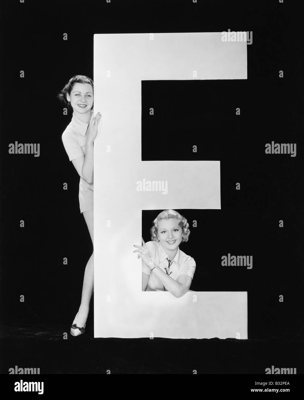 Frauen posieren mit riesigen Buchstaben E Stockfoto