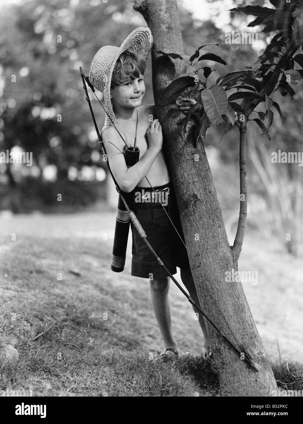 Junge hinter Baum mit Pfeil und Bogen Stockfoto