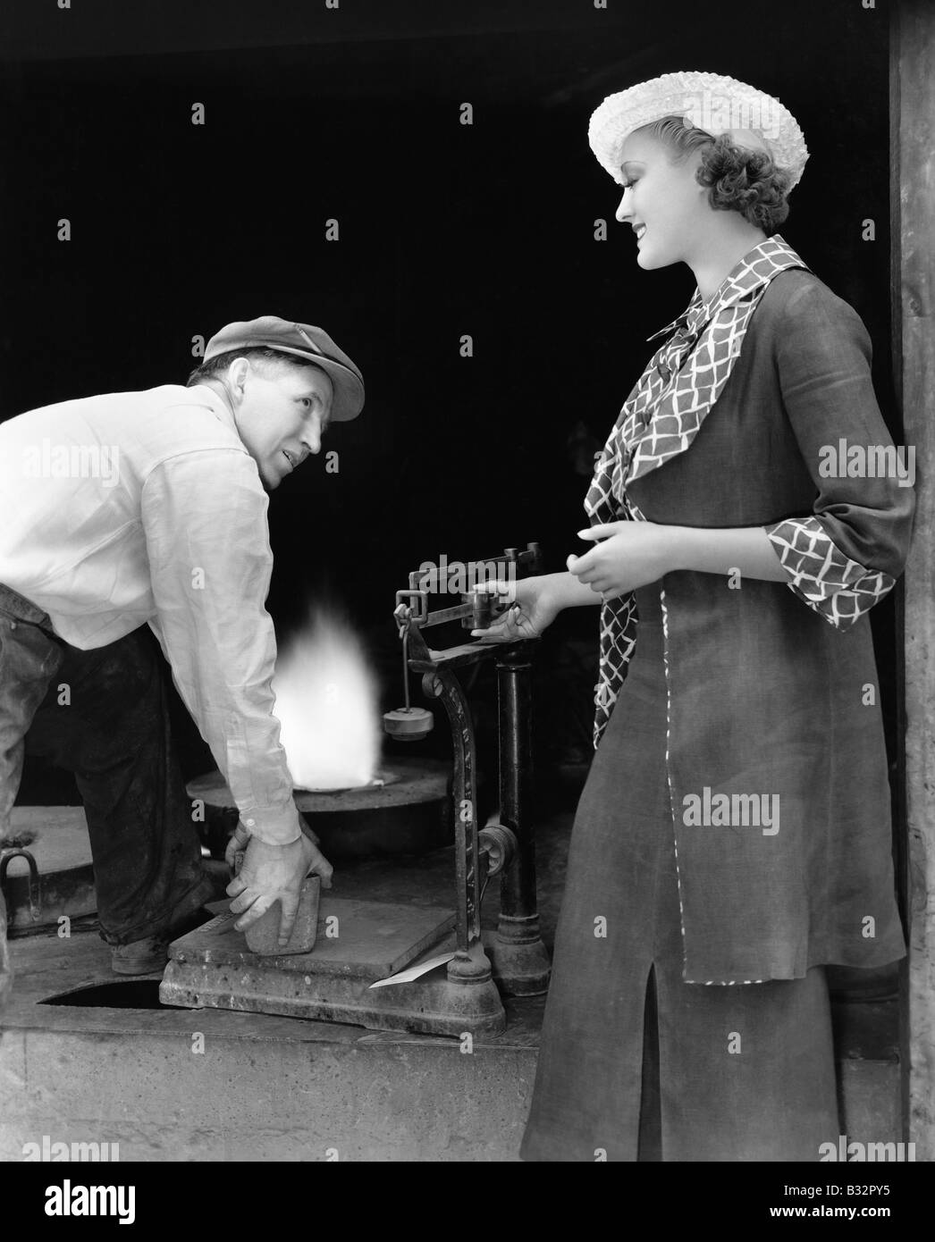 Frau mit Mann am Gießerei mit einem Gewicht von Silber Stockfoto