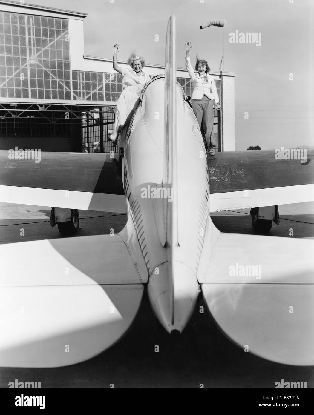 Zwei Frauen winken von den Flügeln eines Flugzeuges Stockfoto