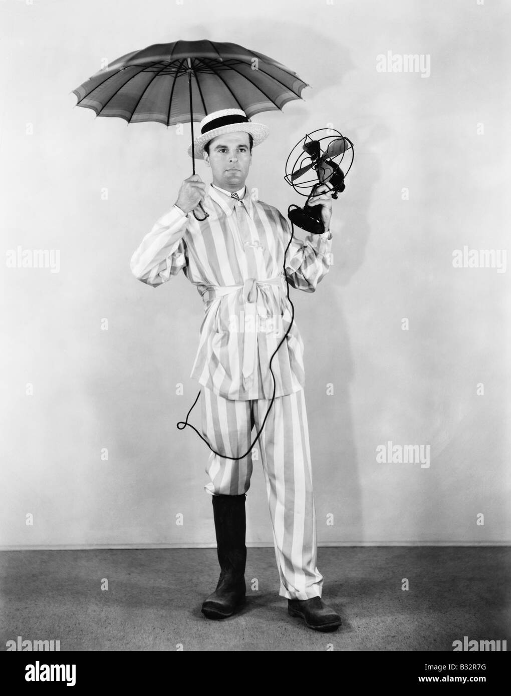 Der Wetter-Mann mit Regenschirm, Boot und Ventilator Stockfoto