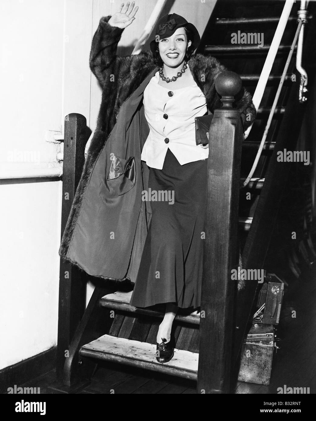 Junge Frau auf einer Treppe winken und Lächeln Stockfoto