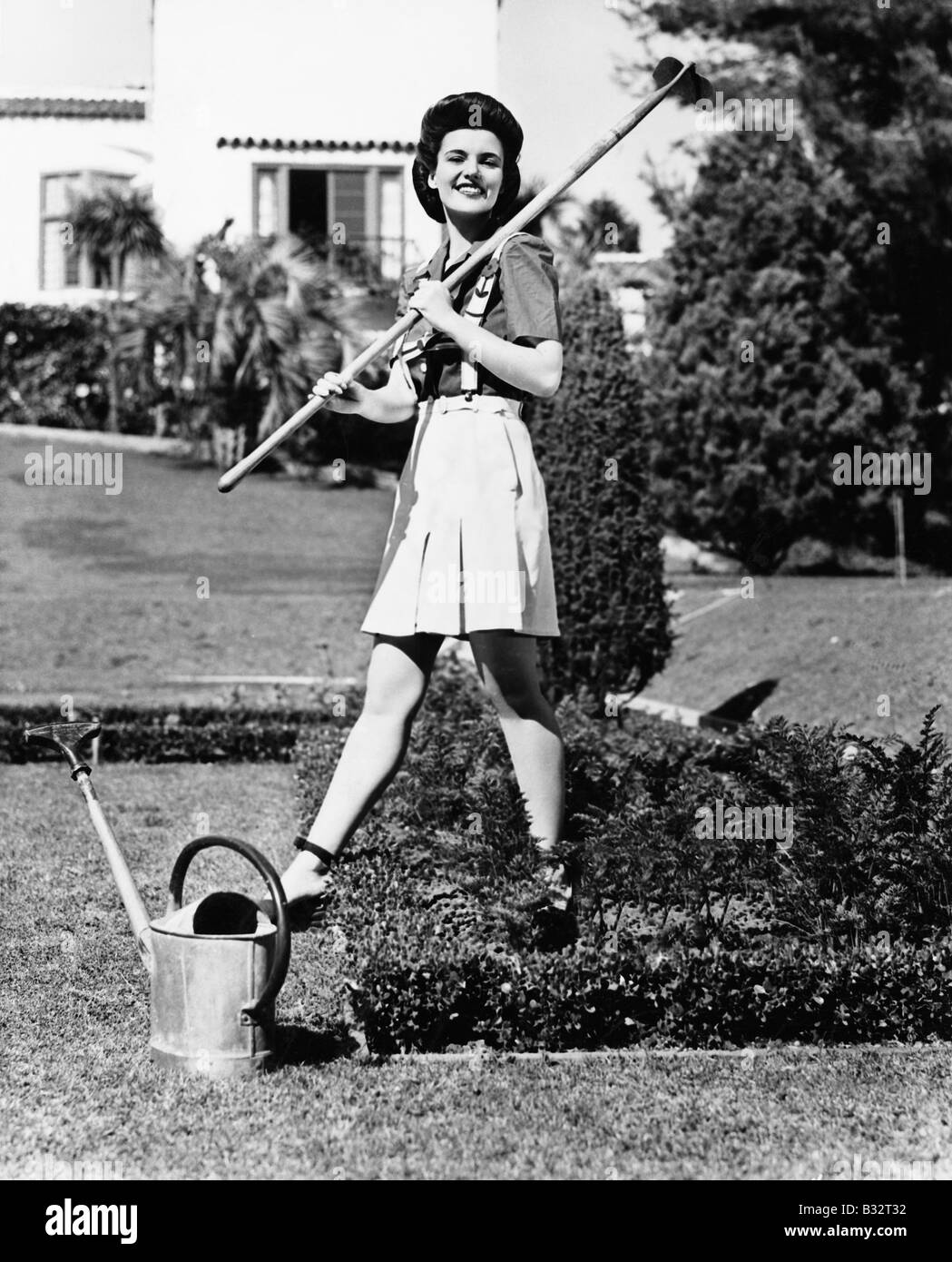 Profil einer jungen Frau mit einer Harke auf die Schulter in einem Garten Stockfoto