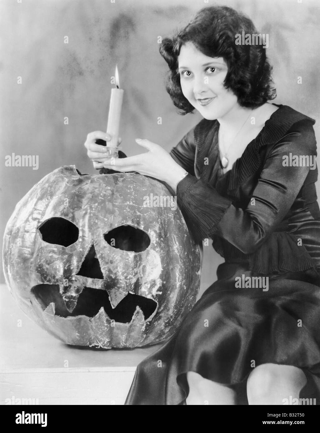 Junge Frau hält eine brennende Kerze auf einem Jack o ' Lantern lächelnd Stockfoto