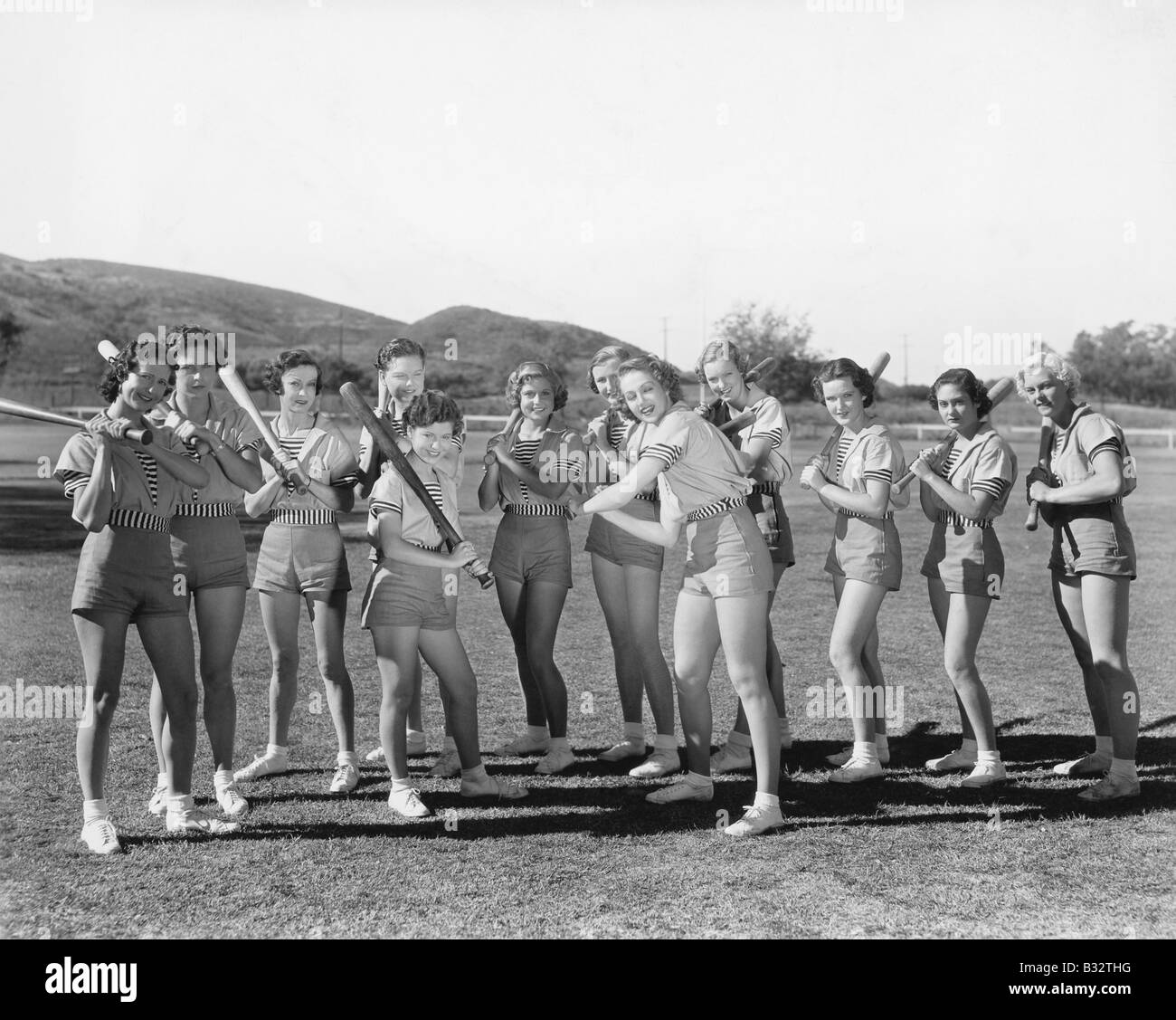 Gruppe von Frauen halten Baseballschläger und stehen in einer Reihe Stockfoto
