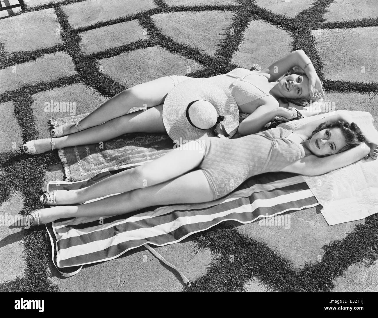 Erhöhte Ansicht zweier junger Frauen, die auf einem Handtuch in der Sonne liegen Stockfoto
