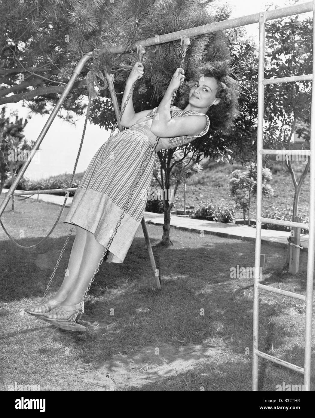 Profil einer jungen Frau schwingen auf einer Schaukel im Garten Stockfoto