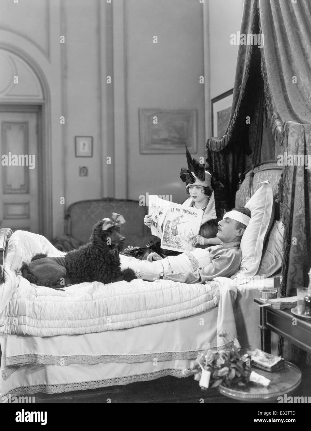Frau und Pudel sitzt neben einem verletzten Mann im Bett Stockfoto