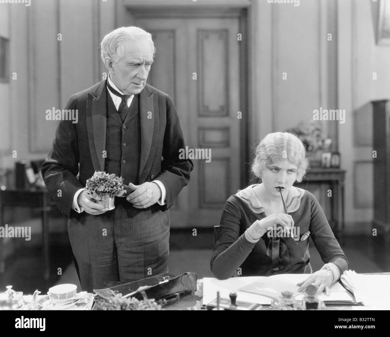 Älterer Mann stand neben einer Frau an ihrem Schreibtisch Stockfoto