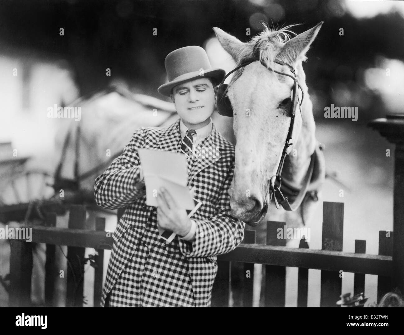 Man liest einen Brief zu seinem Pferd Zaun gelehnt Stockfoto