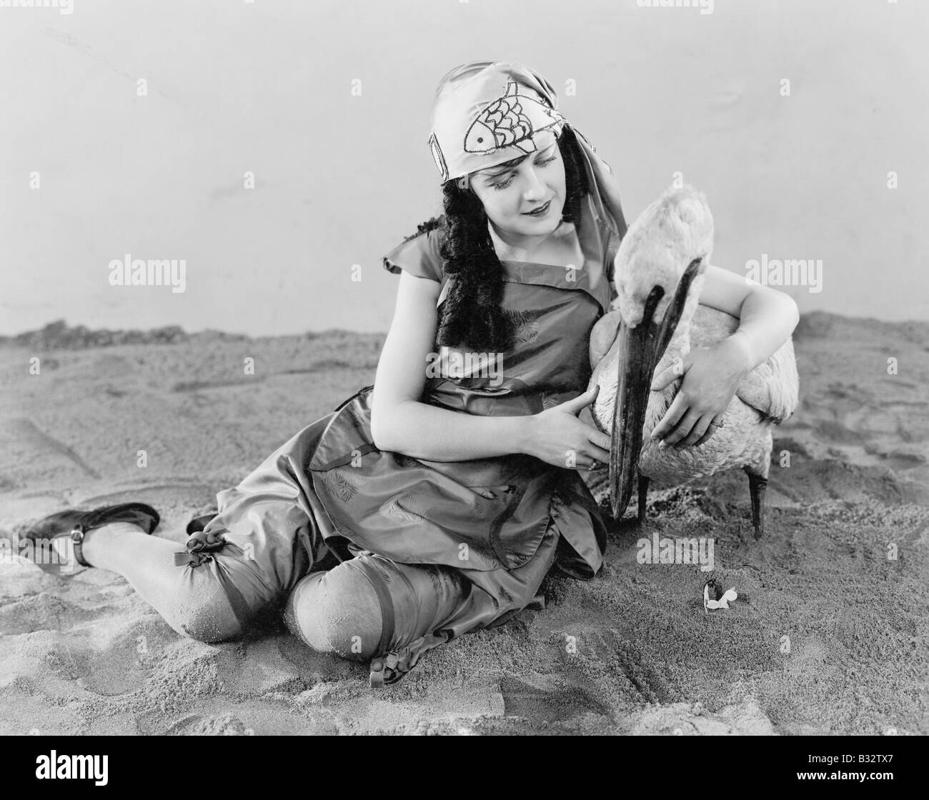 Frau sitzt auf dem Boden ein Pelikan im Arm halten Stockfoto