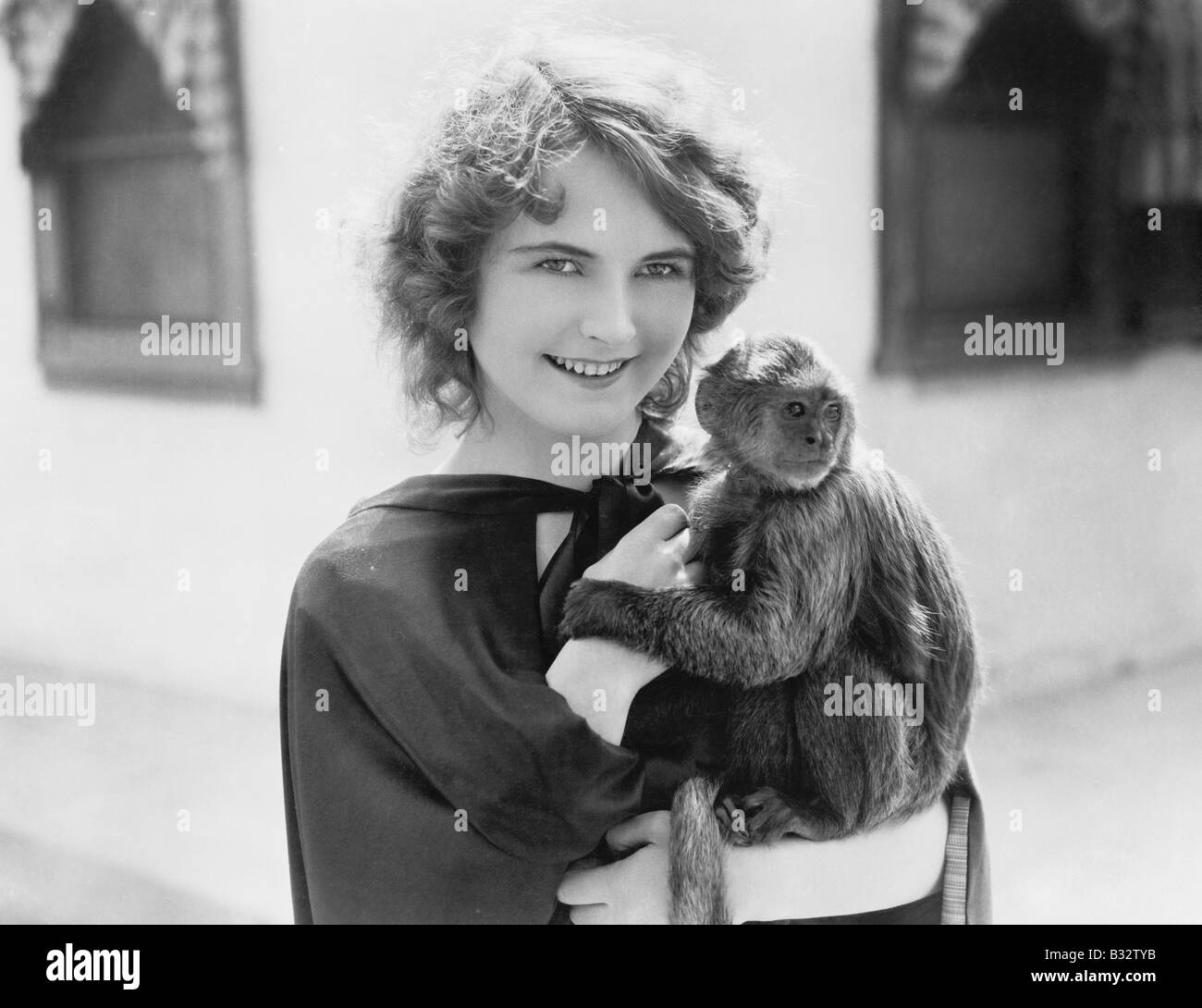 Frau, die einen Haustieren Affen in ihren Armen hält Stockfoto