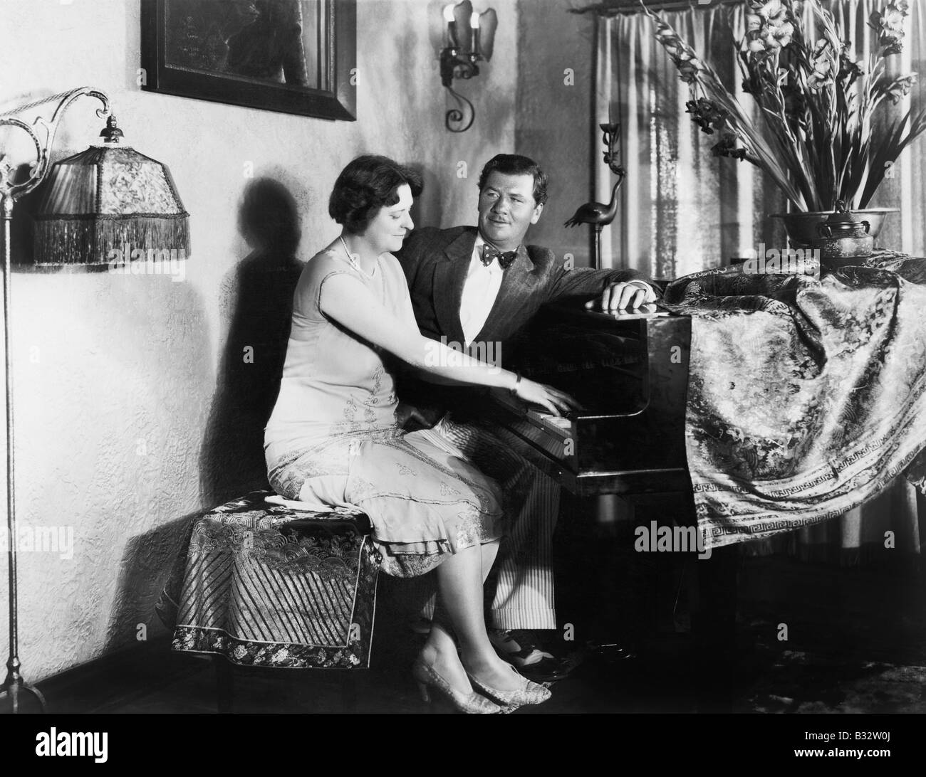 Mann, sitzend mit Frau Klavier spielen Stockfoto