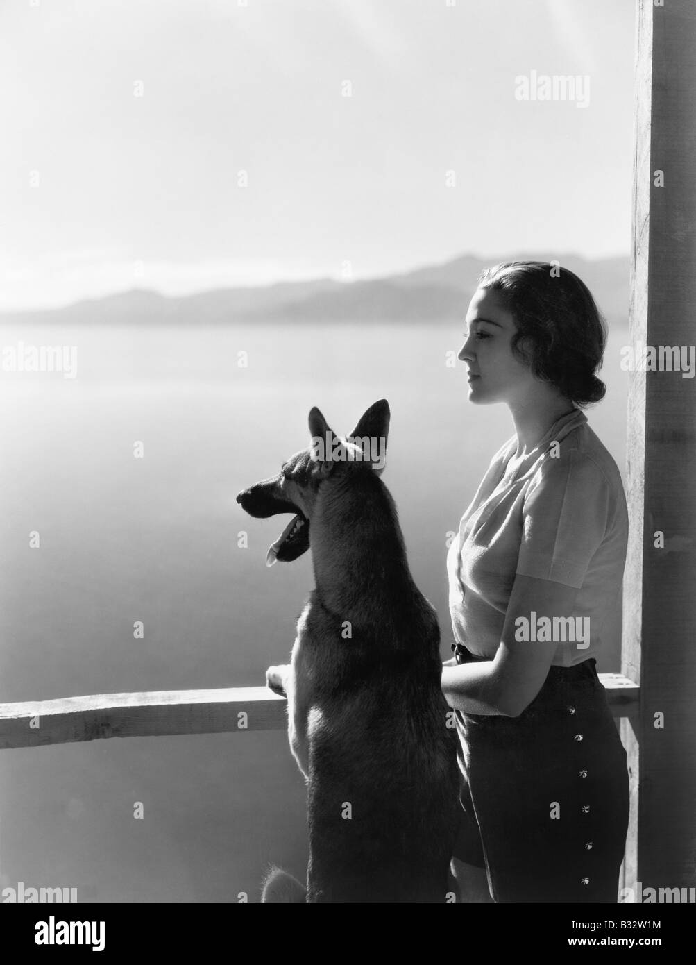 Frau und ihr Schäferhund mit Blick auf einen See Stockfoto