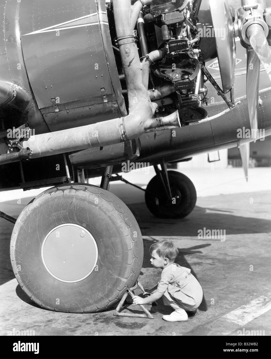 Kleiner Junge versucht, eine Flugzeug-Rad zu beheben Stockfoto
