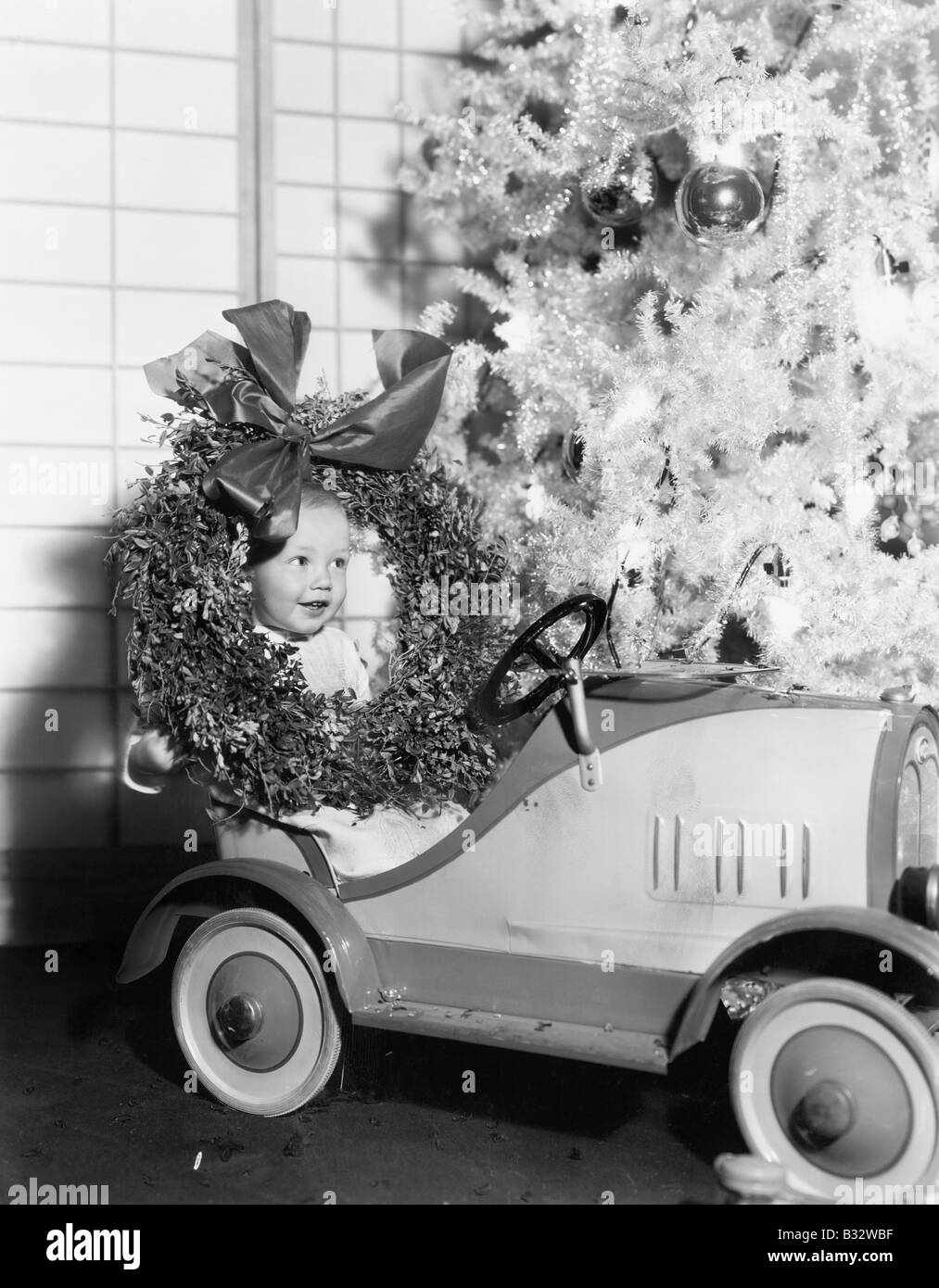 Kleiner Junge an Weihnachten sitzt in seinem Spielzeugauto Stockfoto