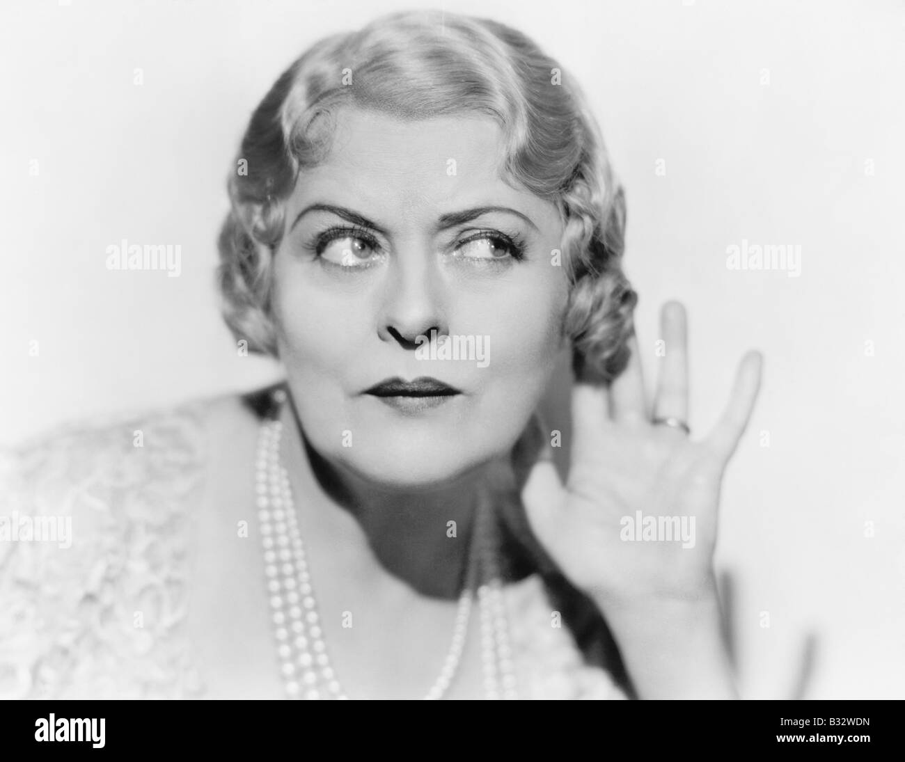 Junge Frau mit und hinter ihr Ohr hören möchten Stockfoto