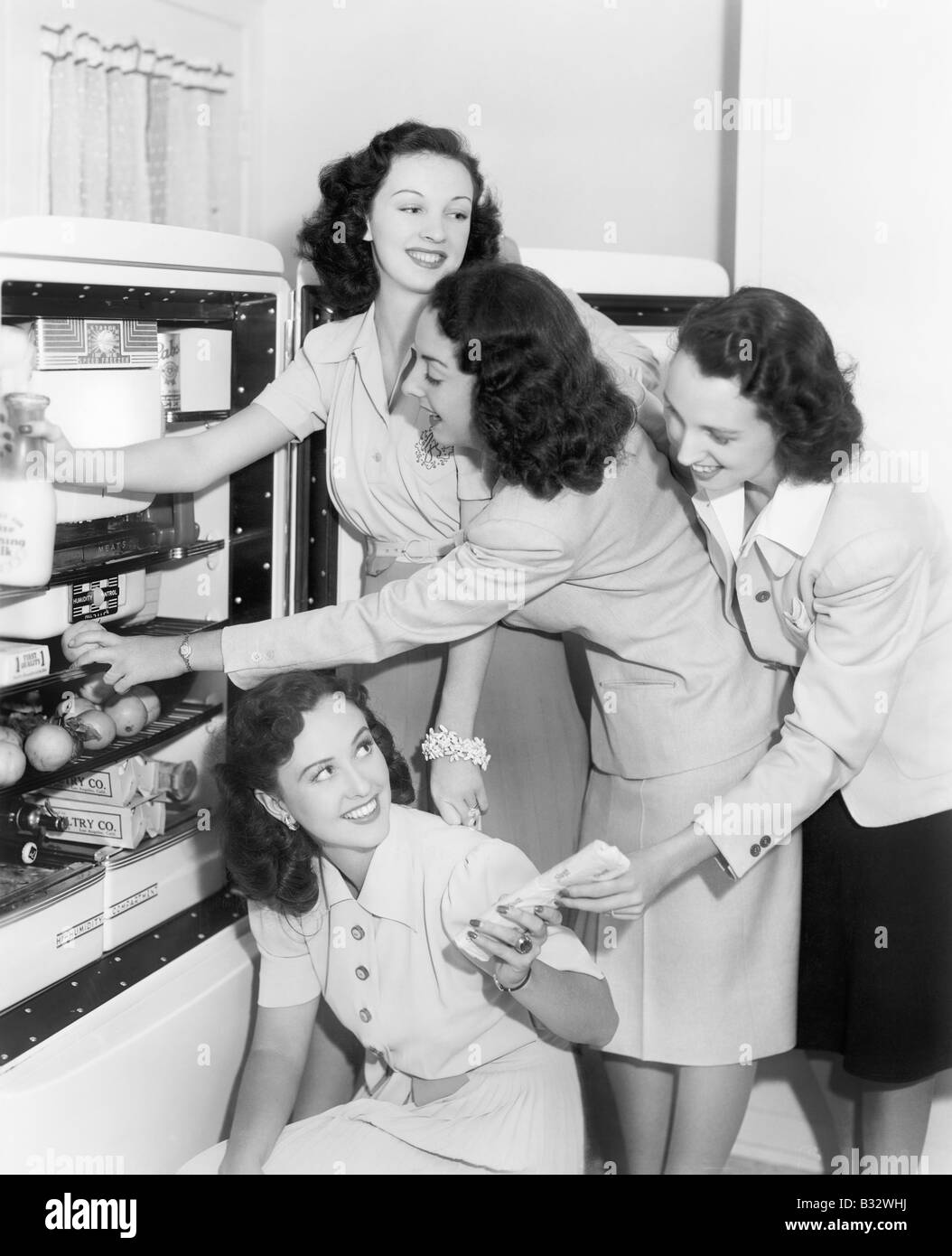 Vier Frauen, die Dinge aus einem Kühlschrank Stockfoto