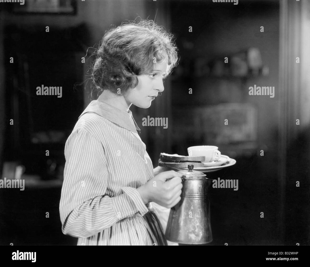 Junge Frau mit einem Topf Kaffee und einen Teller mit Brot Stockfoto