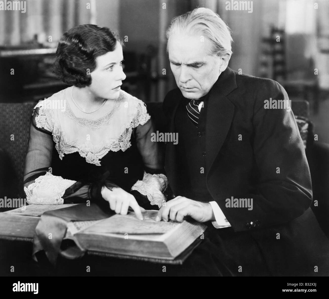 Paar beisammen sitzen und ein Buch mit einem besorgt Gesichtsausdruck betrachten Stockfoto