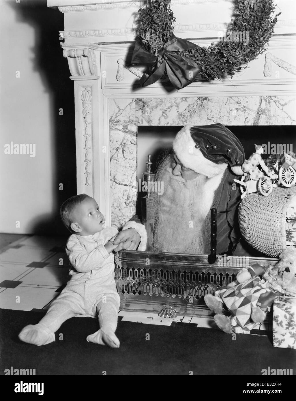Weihnachtsmann mit einem kleinen Jungen vor einem Kamin Stockfoto