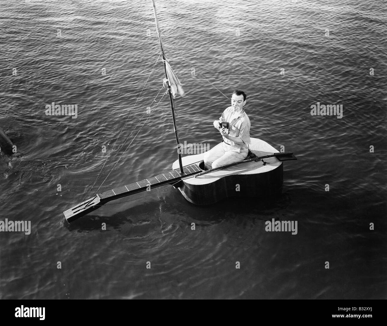 Mann sitzt auf einem Segelboot Gitarre Stockfoto