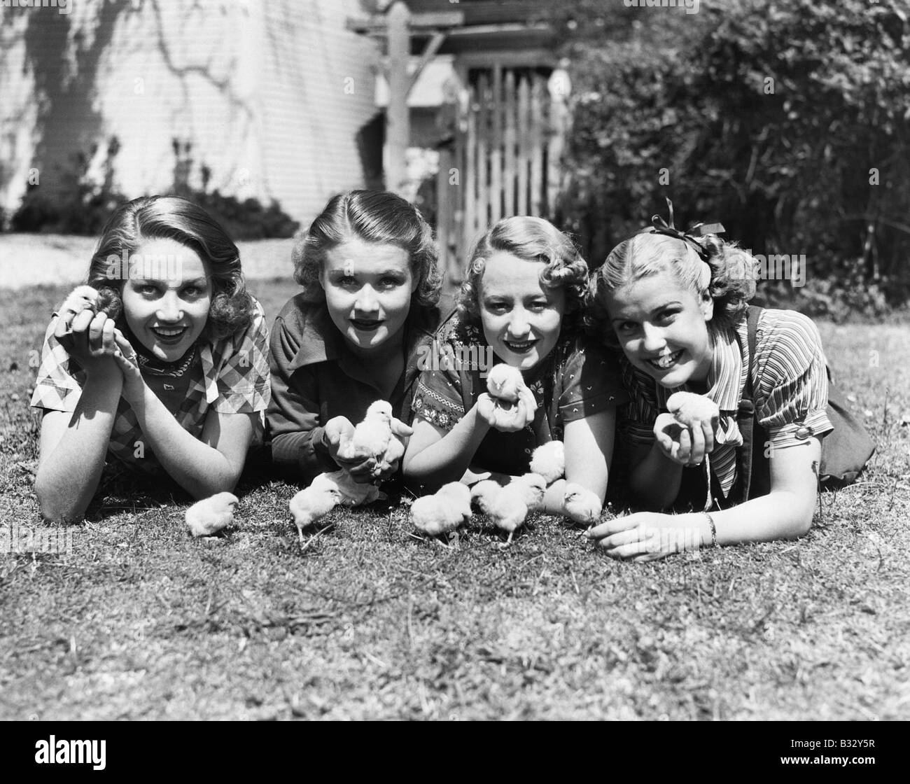 Vier junge Frauen liegen außerhalb mit Küken. Stockfoto